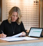Optician reviewing bookkeeping records and financial charts at practice reception desk